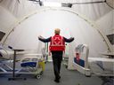 A volunteer with the Red Cross shows a doorway between beds in a mobile hospital set up in partnership with the Canadian Red Cross in the Jacques-Lemaire Arena to help care for patients with the coronavirus disease (COVID-19) from long-term centers ( CHSLDs), in Montreal, Quebec, Canada April 26, 2020. The response to COVID-19 showed what can be accomplished when society mobilizes, the authors say.