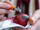 Taïssa Hrycay applies wax to a Ukrainian Easter egg, or pysanka, with a rooster-based design, at her home.