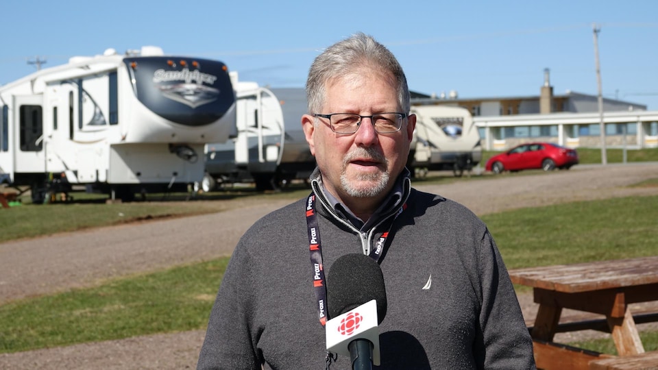 Élie Chevrier is outside, he speaks to the microphone of Radio-Canada in front of trailers.