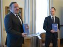 Quebec Premier François Legault , left, receives a copy of the provincial budget speech from Quebec Finance Minister Eric Girard Tuesday, March 22, 2022 at the Premier's office in Quebec City.