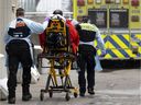 MONTREAL, QUE.: January 13, 2022 -- Paramedics transport a patient suspected of having COVID-19 to the special COVID section of the emergency room at the Notre-Dame Hospital in Montreal, on Thursday, January 13, 2022. 