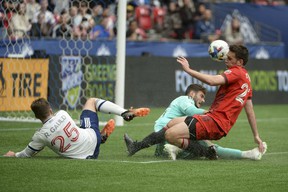 Toronto FC goalkeeper Alex Bono (25) and defender Shane O'Neill (27) defend against Vancouver Whitecaps midfielder Ryan Gauld (25) during the first half at BC Place.