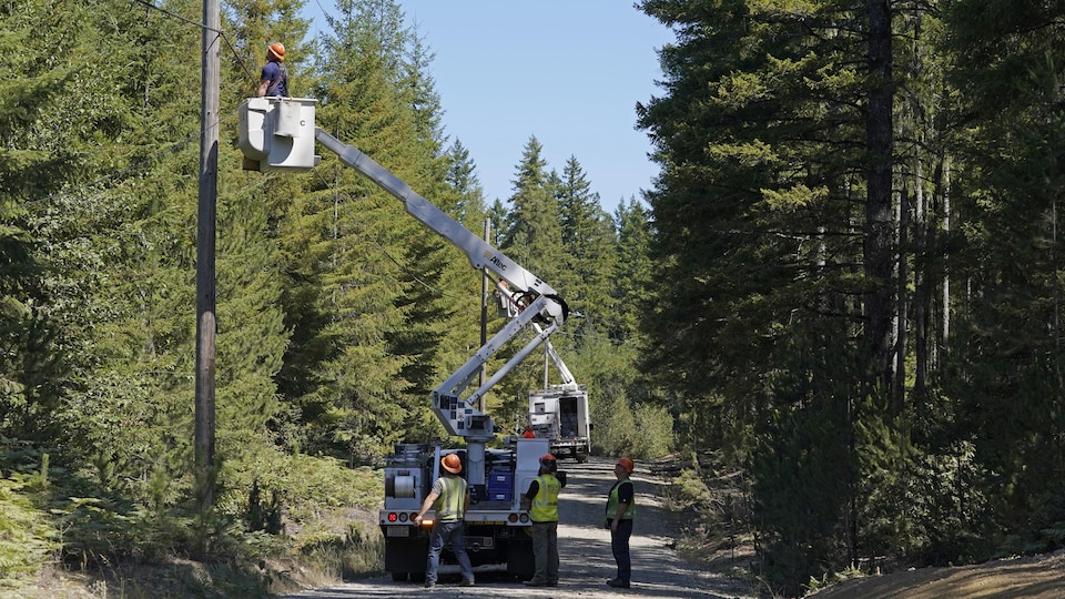Workers install fiber optic cables in a pole using a truck equipped with a basket.