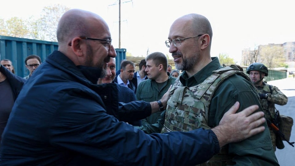 Charles Michel places his hands on the shoulders of Denys Chmygal, who is wearing a bulletproof jacket.