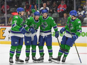 Abbotsford Canucks forward Danila Klimovich (left) and defenseman Jack Rathbone (second from left) celebrates with teammates after a goal was scored earlier this season.