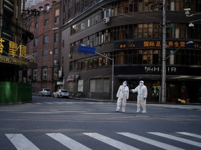 Workers in protective suits guard a street during a lockdown in Shanghai on April 16.