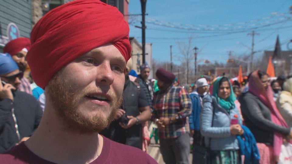 Young redhead man with short beard wearing a red turban.