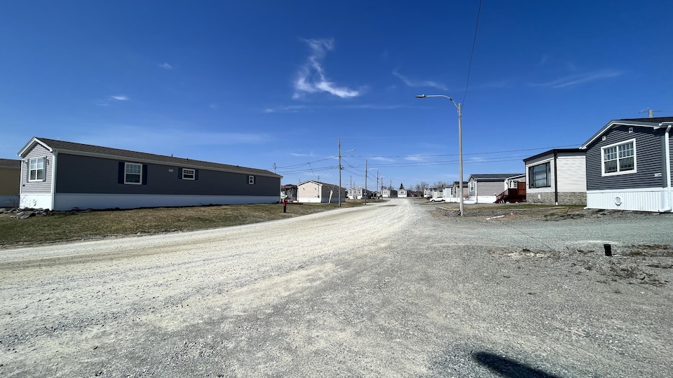 Unimodular houses built side by side on an unpaved street.