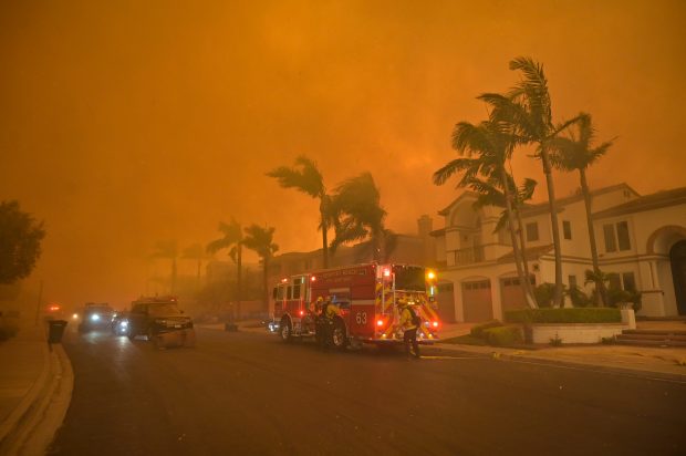 Firefighters battle the Coastal Fire near the intersection of Vista...