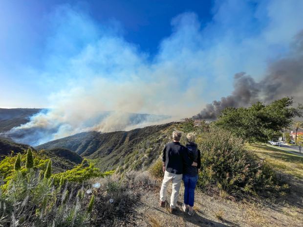 A couple watches the Coastal Fire from a lookout along...