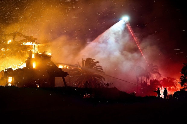 Firefighters work to put out a structure burning during a...