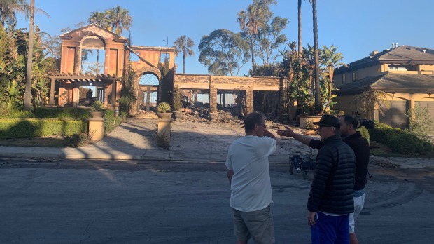 Neighbors whose house survived the Coastal fire survey the damage...
