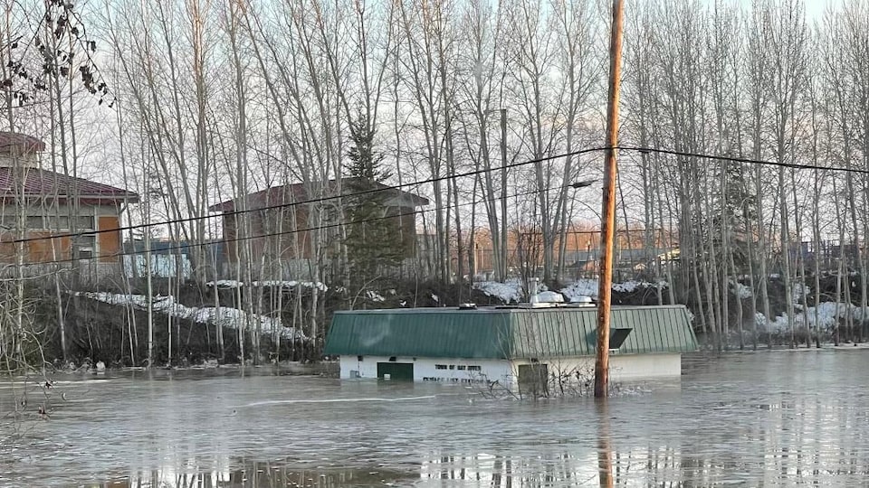 A small building is almost entirely underwater on a street in Hay River.