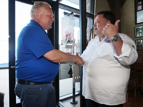 Premier Doug Ford, left, is greeted by Joe Ciaravino, president of Antonino's Original Pizza on Thursday, May 12, 2022. Ford picked up a pizza at the Tecumseh shop during the brief photo op.