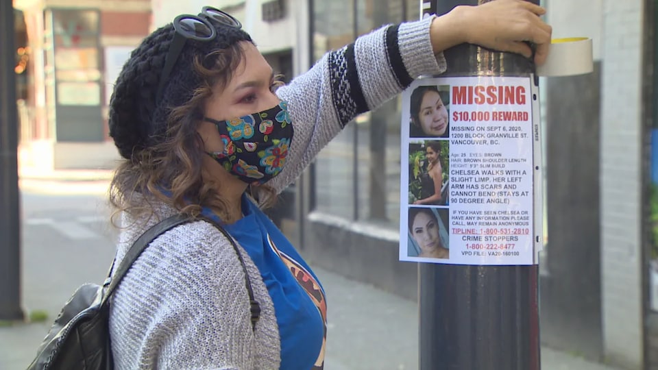 Sheila Poorman sticks a wanted poster protected by a transparent plastic envelope on a pole on Granville Street in downtown Vancouver.