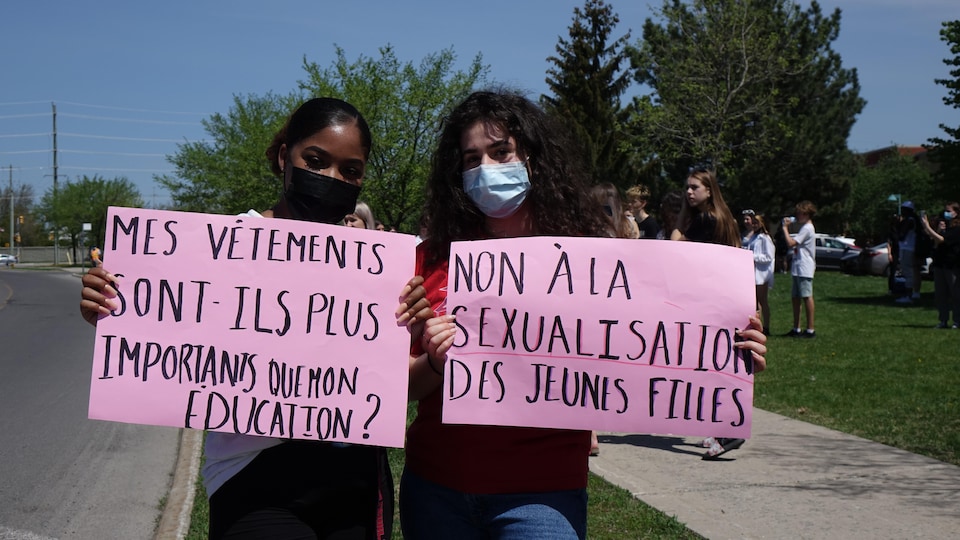Two young girls are holding signs