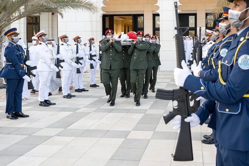 Soldiers carry the body of the late president through the honor guard.