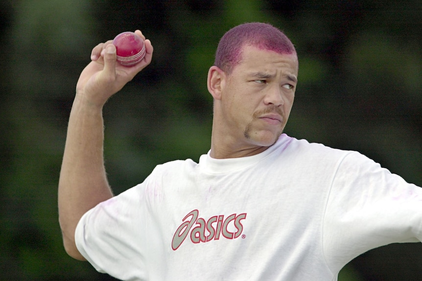 A young Andrew Symonds, with maroon-dyed hair, bowls a cricket ball