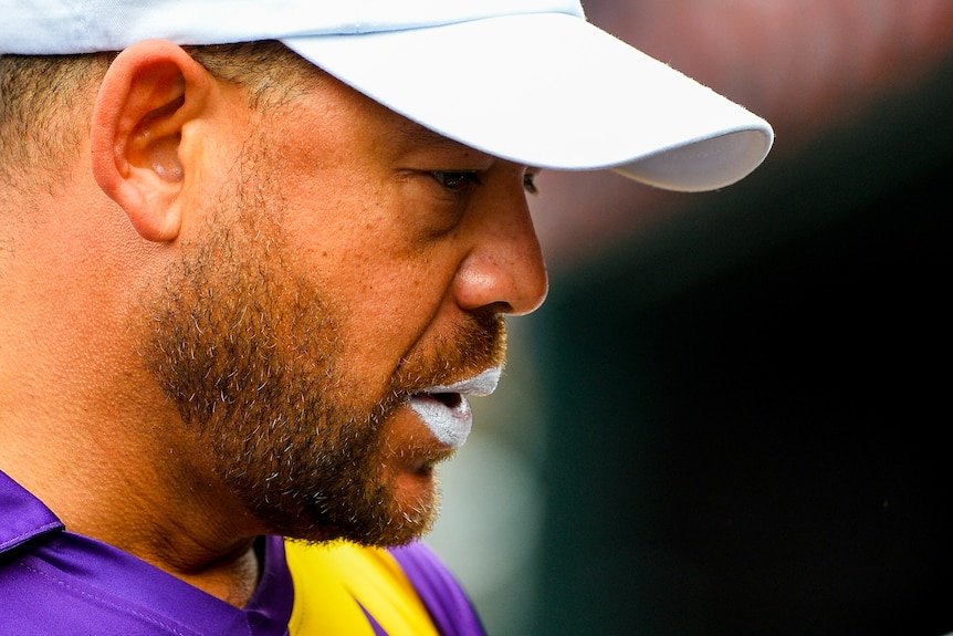 Andrew Symonds looks down while wearing a white cap
