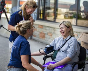 Nataliya Sobetca, who is eight months pregnant and among a group of people fleeing the war from Ukraine, receives a check-up from volunteer nurses Kim Wiebe (top) and Marcella Veenman-Mulder, after arriving at a terminal at Toronto Pearson airport on a plane from Poland, operated by Samaritan's Purse Canada on Sunday, May 15, 2022. ERNEST DOROSZUK/TORONTO SUN