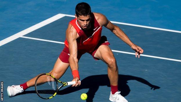 Carlos Alcaraz stretches for a half-volley during the 2022 Australian Open