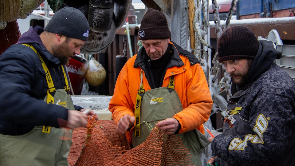 Réjean Richard, Rémy and Martin Element, rework the ship's fishing net to be able to go back to sea.   