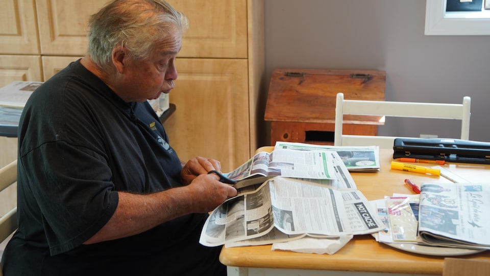 A man cuts up newspaper articles. 