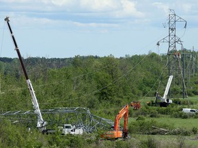 Crews work atop a damaged hydro tower as another lies crumpled in front of it along Highway 417 near Hunt Club Road Monday.