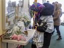 A woman looks at flowers dropped off by well wishers at the Center Culturel Islamique de Québec in Quebec City in February 2017 after people were allowed back inside for the first time following a mass shooting that killed six Muslims.