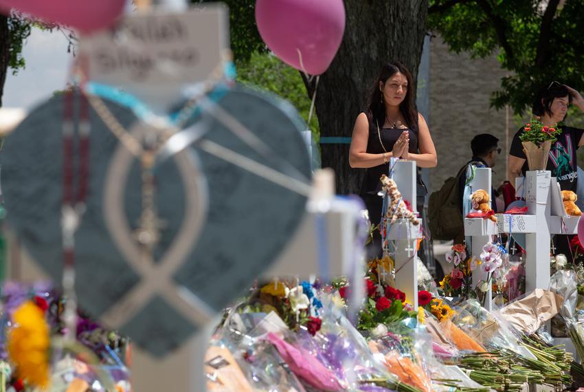 A woman prays at a memorial in honor of the 21 victims killed at a school shooting in Uvalde, on May 27, 2022.