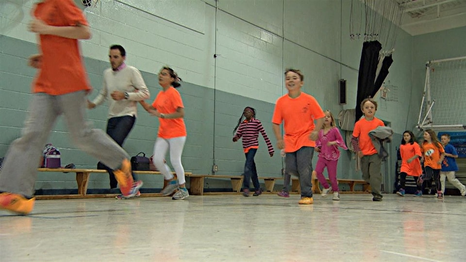 Students run in the gymnasium of an elementary school. 