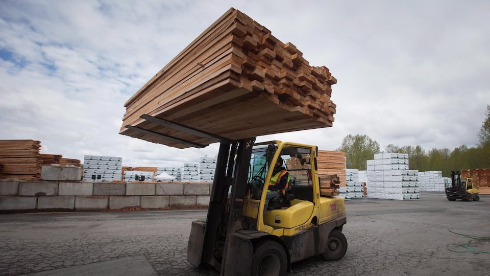 A forklift moves wooden planks.