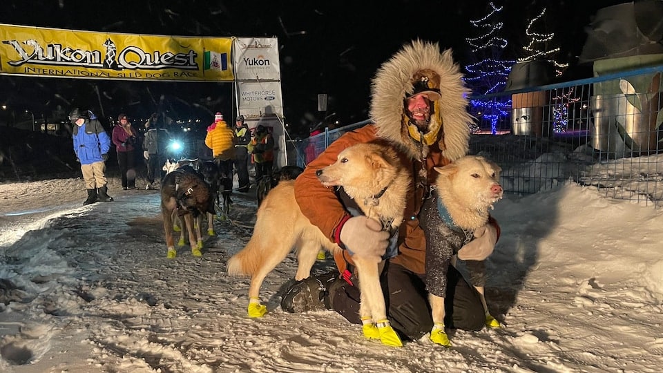 Brent Sass poses at the finish line with his two lead dogs.