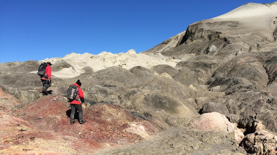 Two researchers walk on a geological formation in the NWT.