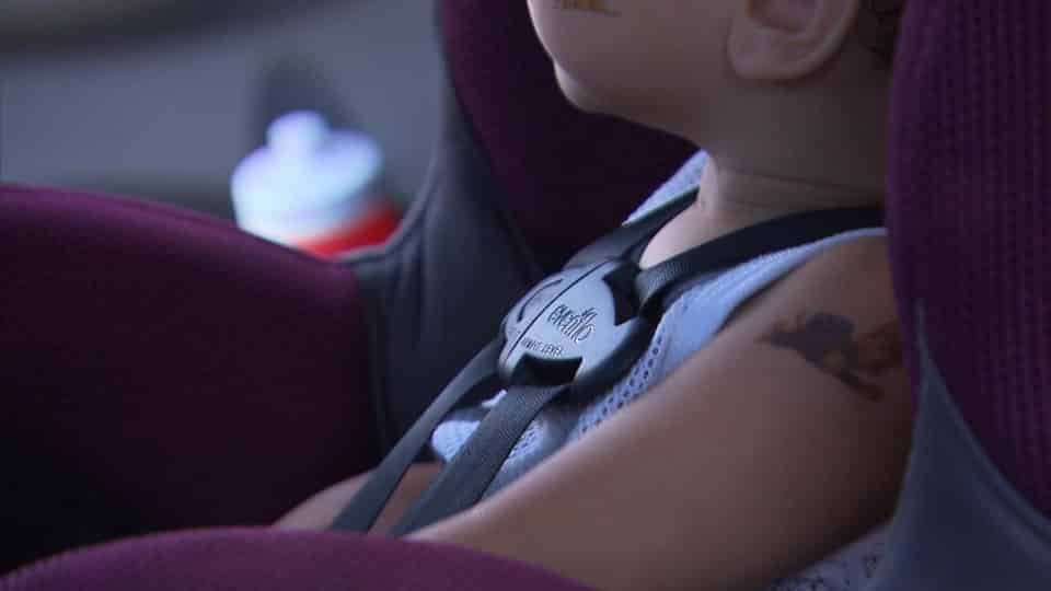 A child is sitting in a car seat with the seat belt buckled.