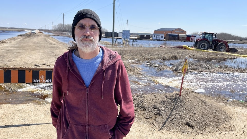 Paul Bélair is standing next to a flooded field and a severed road in Saint-Laurent, Manitoba.