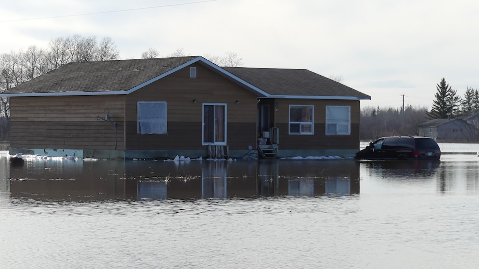 A house and car surrounded by flooding in Peguis First Nation in Manitoba on May 3, 2022.