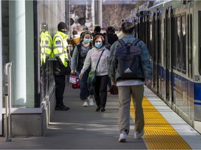 A security guard stands on duty as passengers make their way through the Health Sciences/Jubilee LRT station on Thursday, April 28, 2022. In April a 78-year-old woman was pushed onto the tracks at the station.