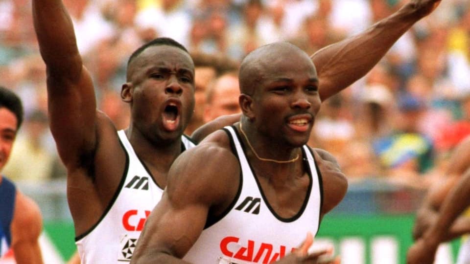 Bruny Surin raises his arms in the air after passing the baton to Donovan Bailey in the 1996 4x100m final in Atlanta.