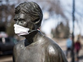 A mask on the statue of Order of Canada recipient Denny Carr in downtown Saskatoon.