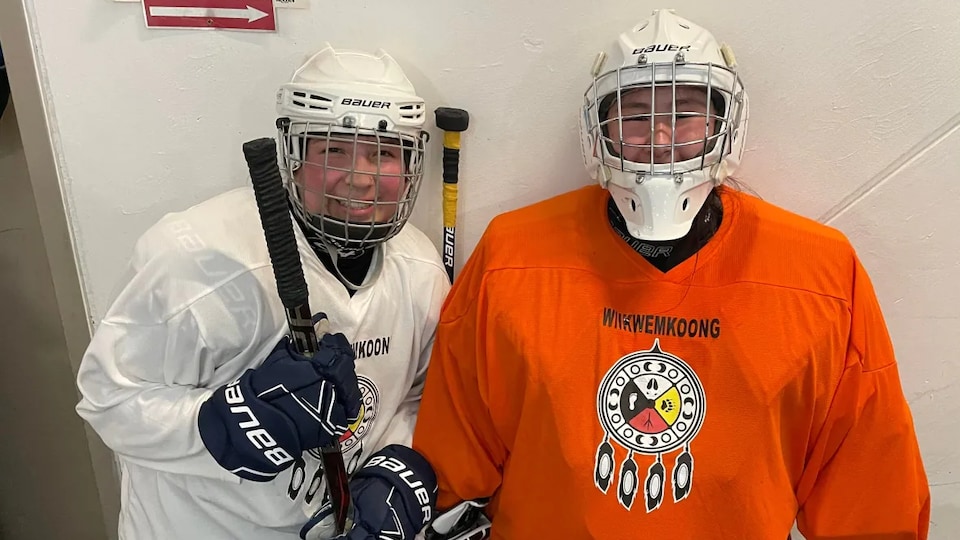 Two female hockey players in game equipment. 