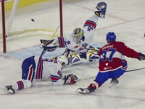 Brandon Gignac of the Laval Rocket scores on goalie Aaron Dell of the Rochester Americans at Place Bell in Laval on Monday, May 23, 2022. Defenseman Brandon Davidson also tries to stop the shot.