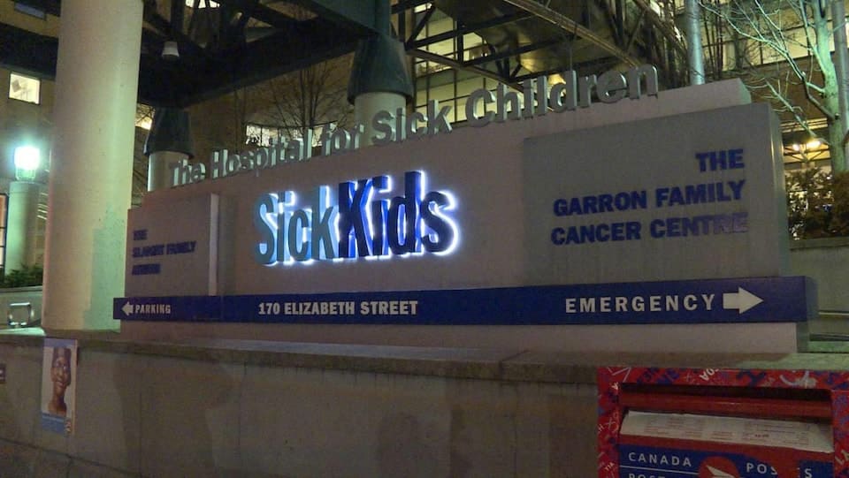 Illuminated sign in front of a building that indicates the name of the hospital as well as different directions