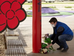 Boyle Street executive director Jordan Reiniger arranges flowers at a memorial in Kinistinâw Park, where three men died of apparent drug poisonings in May 2021.