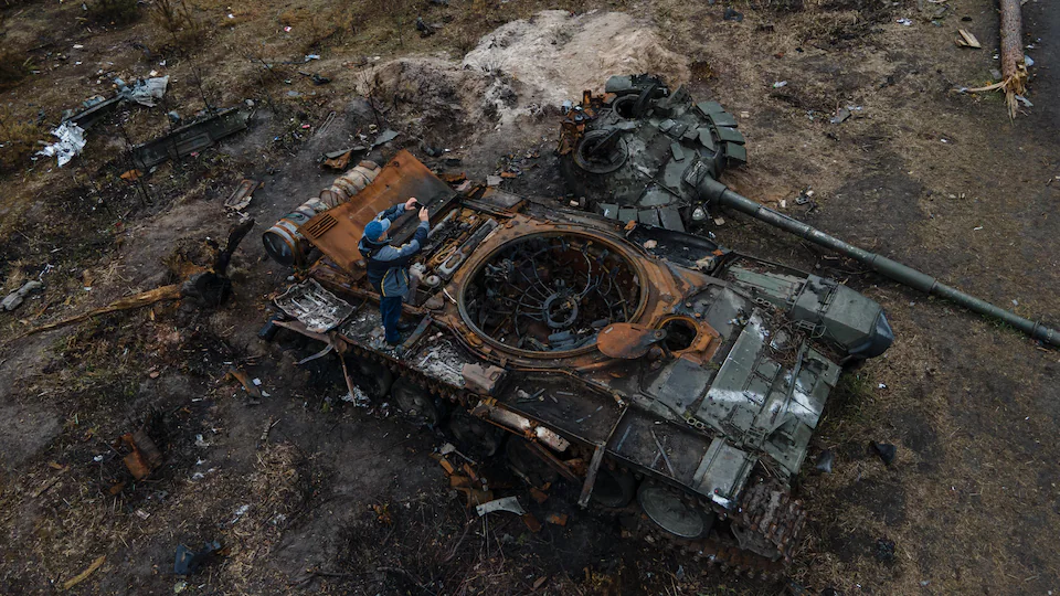 Un homme prend une photo d'un blindé de l'armée russe détruit.