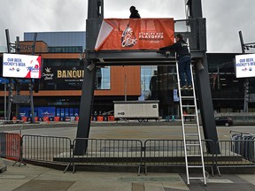 Workers putting up banners as preparations are underway in the Ice District Plaza to welcomed fans and watch on the big screens the Oilers playoff game one on Monday in Edmonton, May 1, 2022.