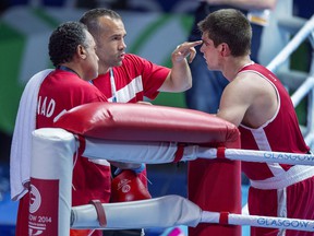 Canada's Brody Blair from New Glasgow, NS talks with coaches Daniel Trepanier and Kevin Howard, left, after fighting Abdul Bangura of Sierra Leone in 75 kg boxing action at the Commonwealth Games in Glasgow, Scotland on Saturday, July 26, 2014.
