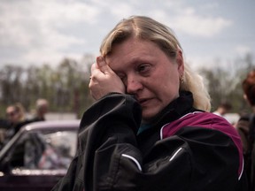 Nadiajda Vorotylina reacts after arriving with her family from the besieged city of Mariupol in their own vehicle, ahead of an expected humanitarian convoy at a registration and processing area for internally displaced people in Ukraine, in Zaporizhzhia, Monday, May 2, 2022.