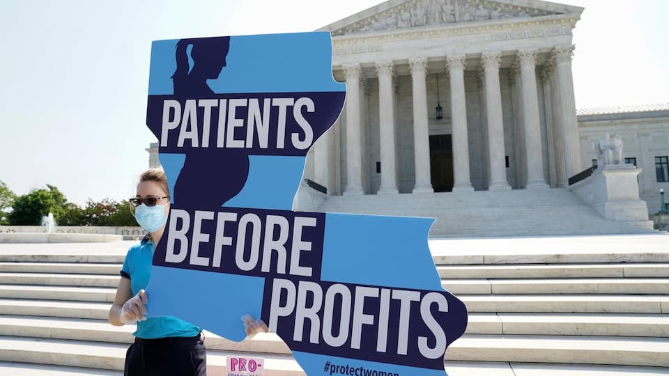 An anti-abortion protester holds up a poster that reads: 'Patients before profits'.