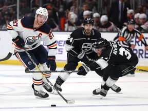 Connor McDavid #97 of the Edmonton Oilers skates with the puck past Viktor Arvidsson #33 and Phillip Danault #24 of the Los Angeles Kings during a 3-2 Oilers win at Crypto.com Arena on April 07, 2022 in Los Angeles, California.